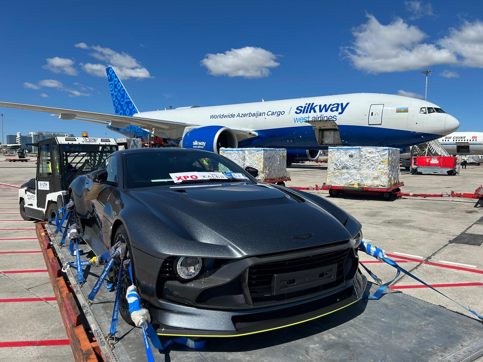 Supercar secured on cargo pallet in front of Silkway West Airlines cargo aircraft